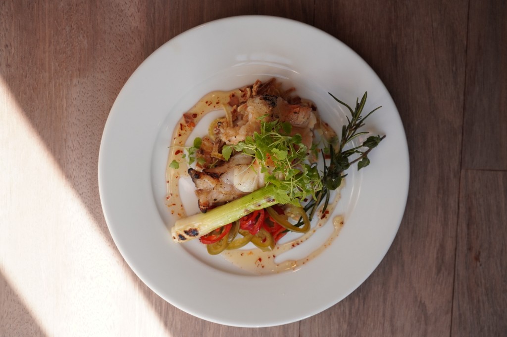 Char-grilled fish with herbs and pickles plated in warm afternoon light